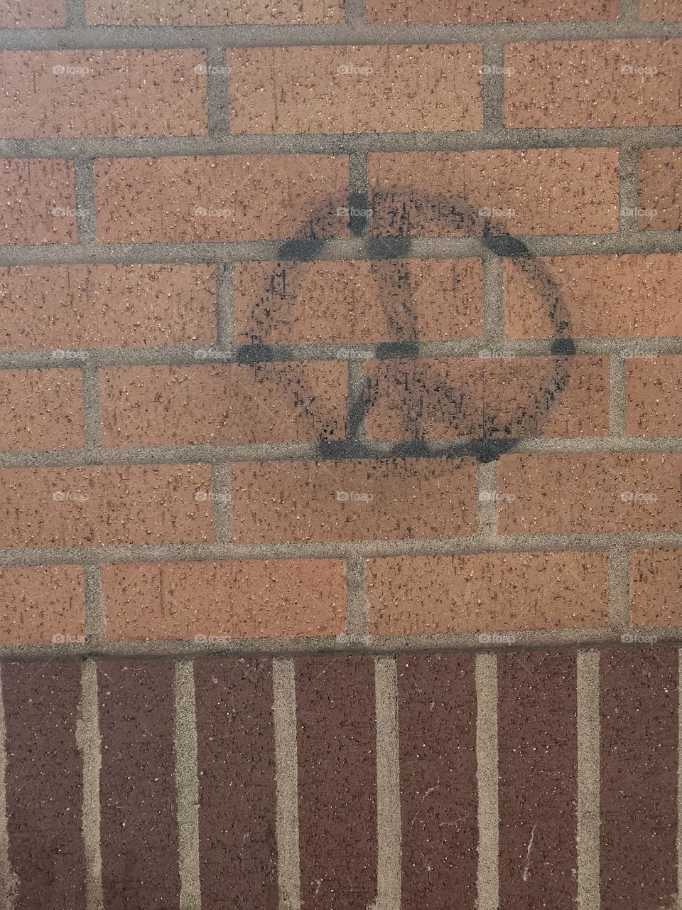 black peace symbol graffiti on brown brick wall