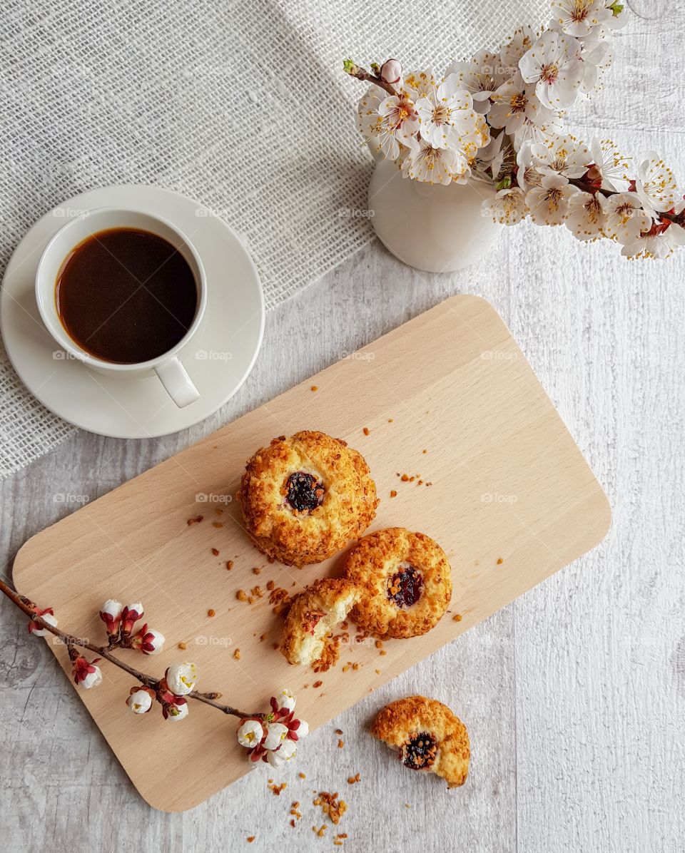 Still life made by black coffee, cookies and some flowered branches.