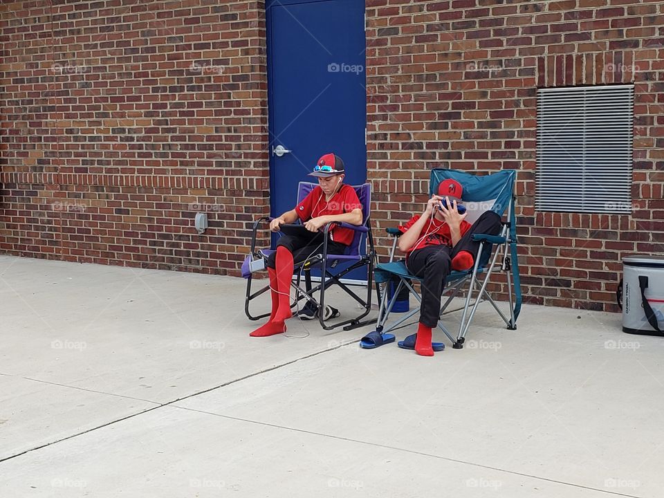 Break time at the ballgame playing on our gadgets