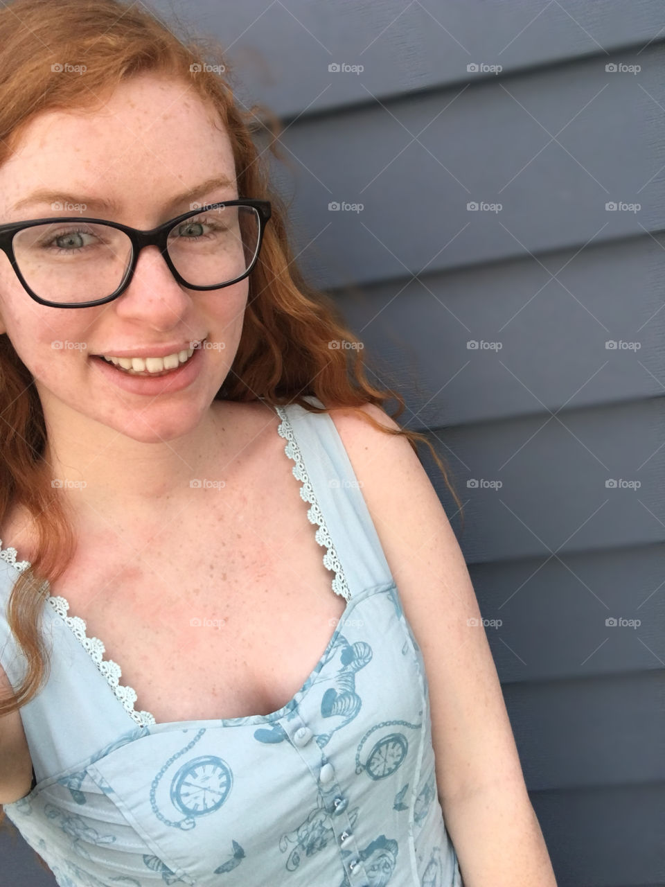Picture of me: red head, blue eyes, freckles, and glasses wearing blue dress with dark blue background