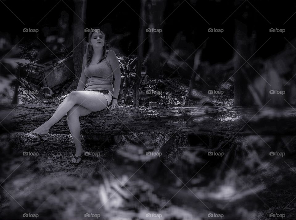 Young woman sitting on tree trunk