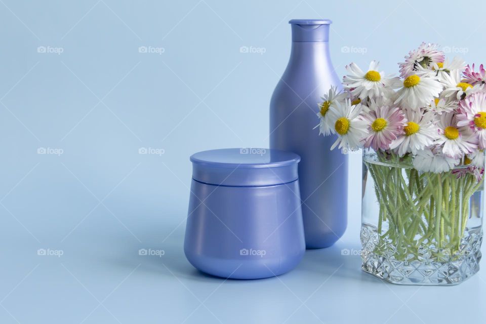 Jars with cosmetic products, beauty cosmetics in purple jars with fragrant flowers.