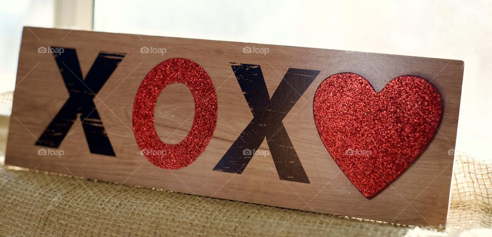 X's and O's and a heart on a wooden board 
