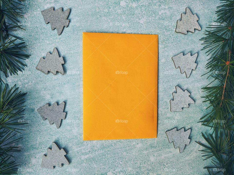 Christmas or New Year composition.  Paper yellow envelope with fir branches on a blue background. Flat lay. Top view.