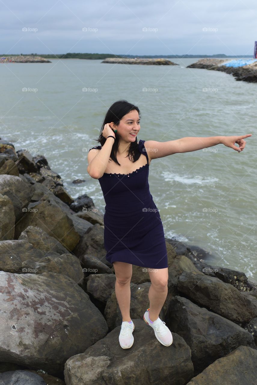 Young woman points to the horizon of the sea very happy