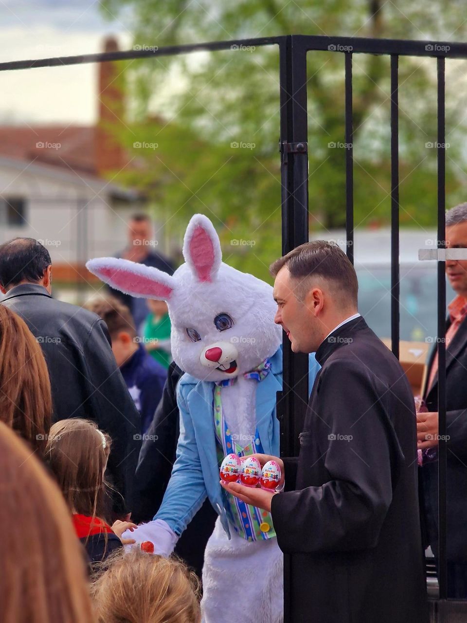 the Easter bunny next to Popa distributes kinder eggs to the children