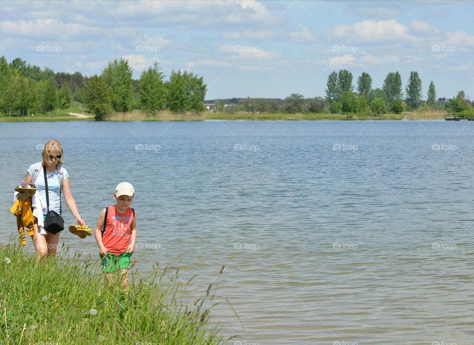 mother and son walking in water lake shore summer vacation, happy family