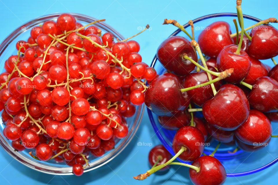 red berries cherry and cranberries on a plate blue background