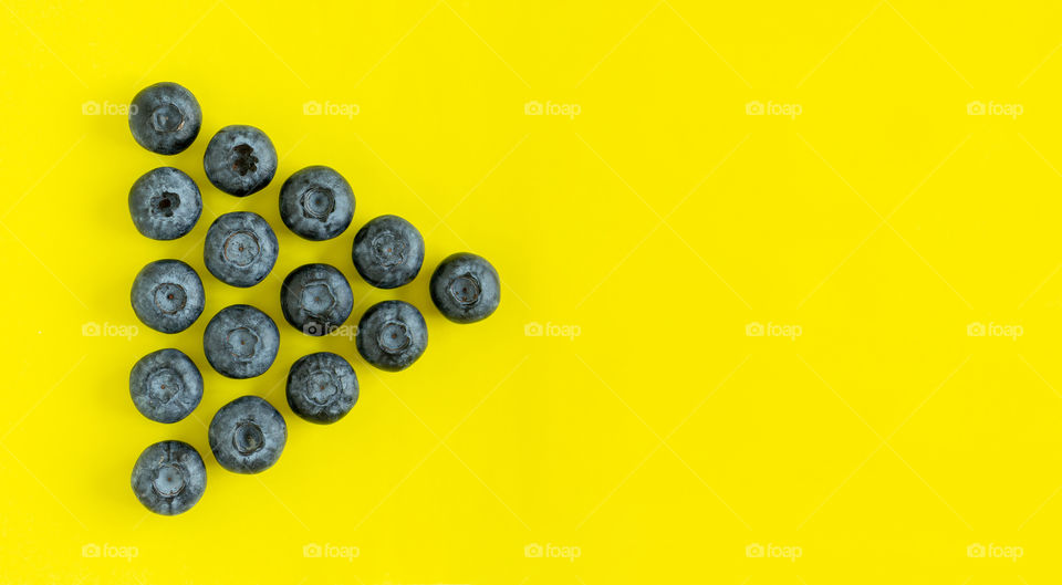 Organic fresh blueberries on bright yellow background