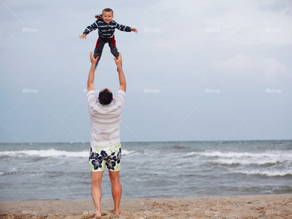 Dad playing with his son on the beach.