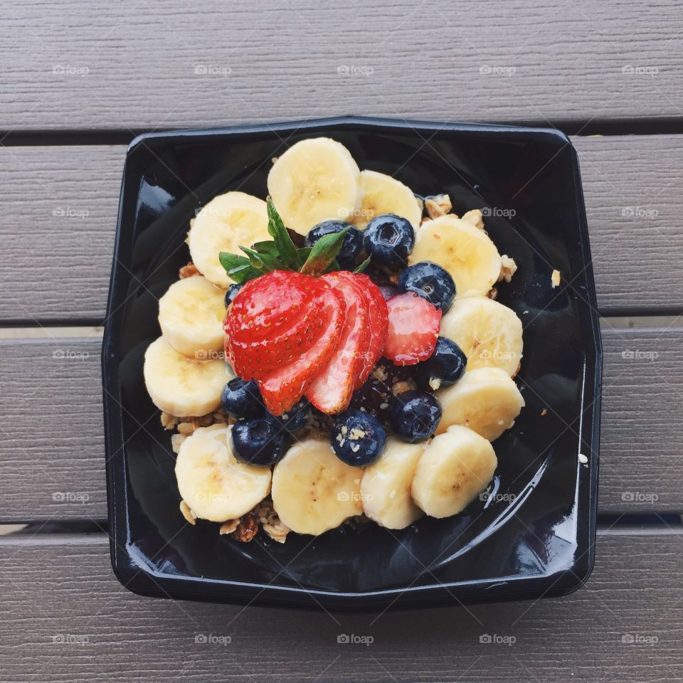 Açaí bowl with granola and fruits on table shot from above. Healthy eating. Fruits, blueberries, bananas, strawberry. 