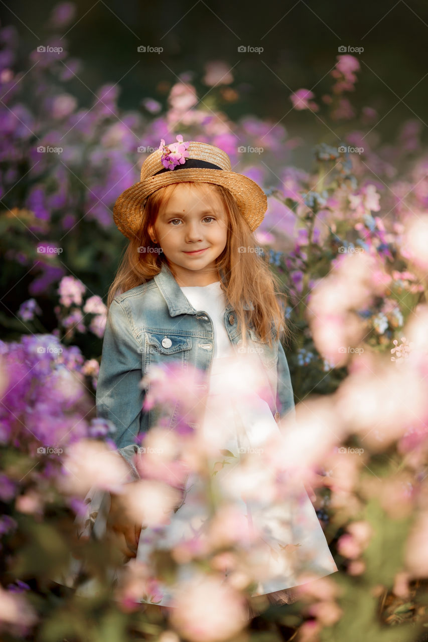 Cute little girl portrait in blossom meadow at sunset 