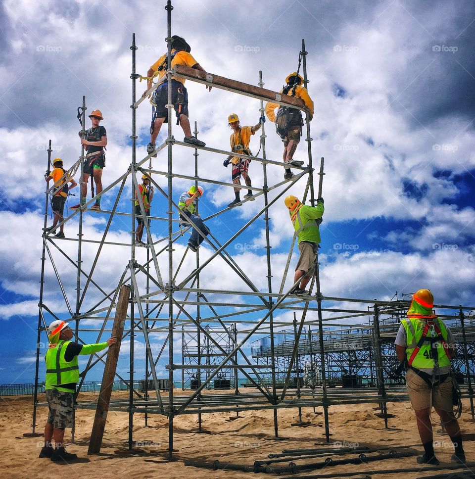 Workers assembling scaffolding for bleachers on a beach