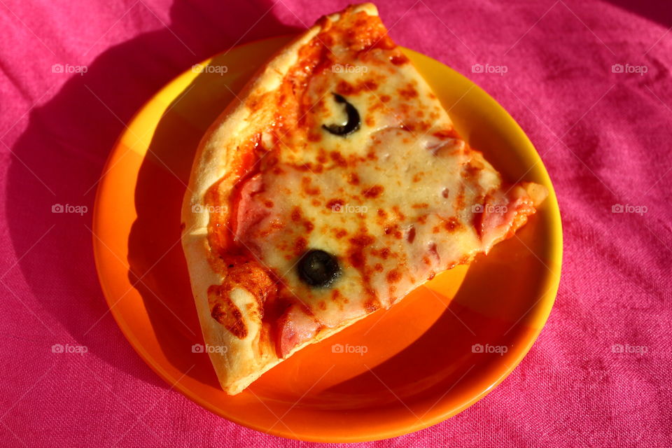 Slice of pizza in a orange plate on a pink background
