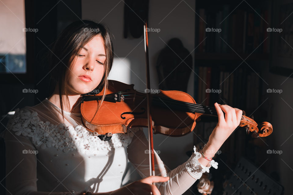 Girl holding a violin in the house