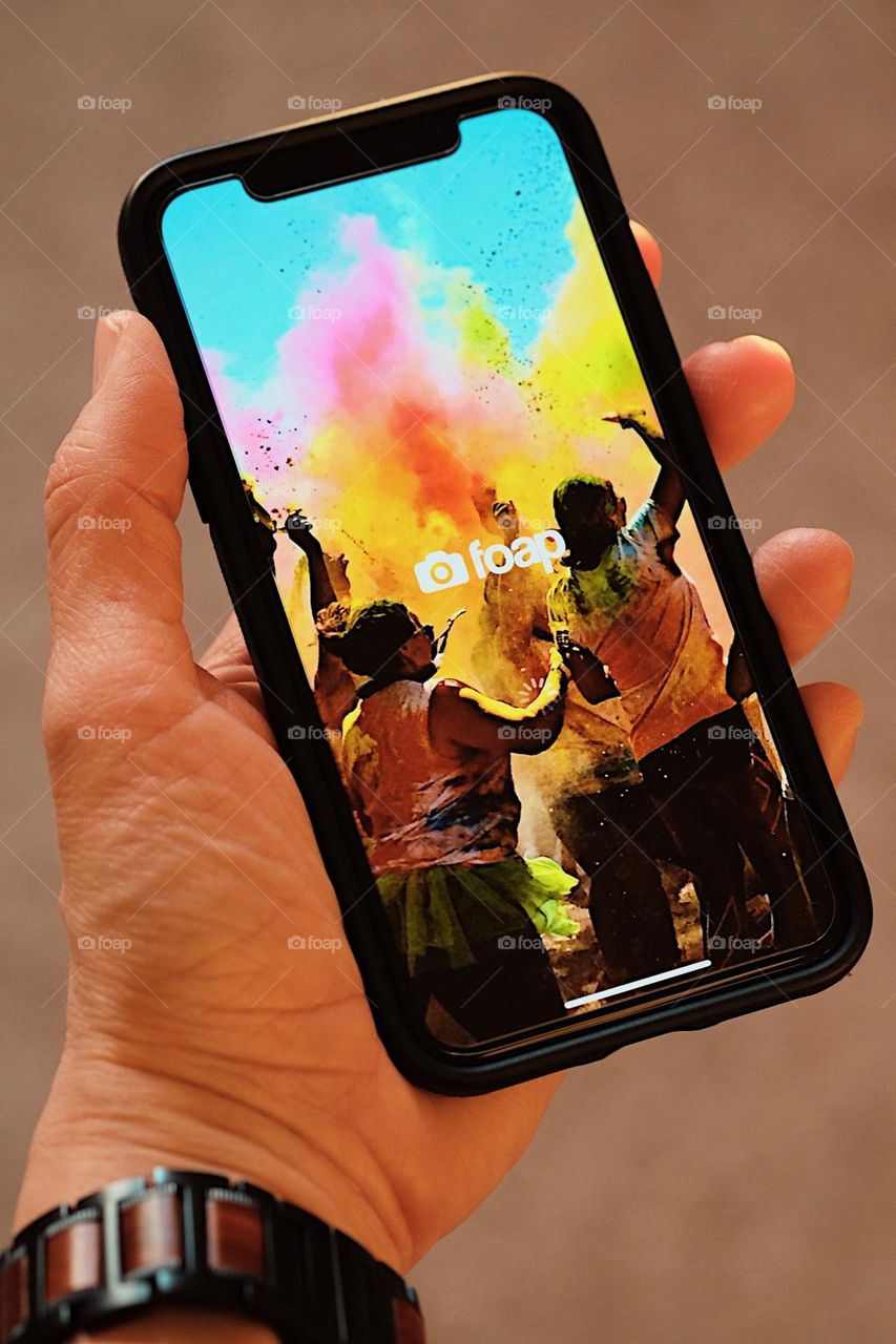 Woman using iPhone, woman’s hand holding phone, woman using phone to use Foap app, woman using phone, point of view, looking down