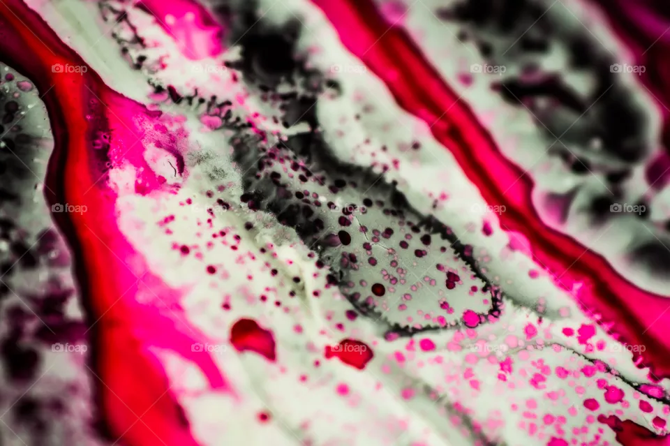 Black and pink refill ink spilled onto the white sink and the ink mixed into abstract blobs and patterns.