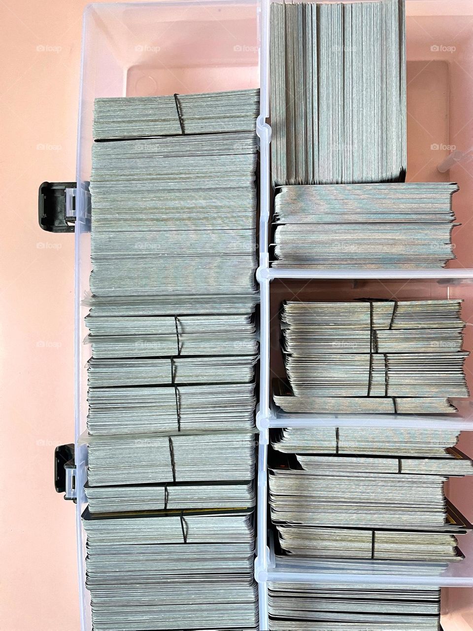 Top view of many playing cards filed in a box on pink table