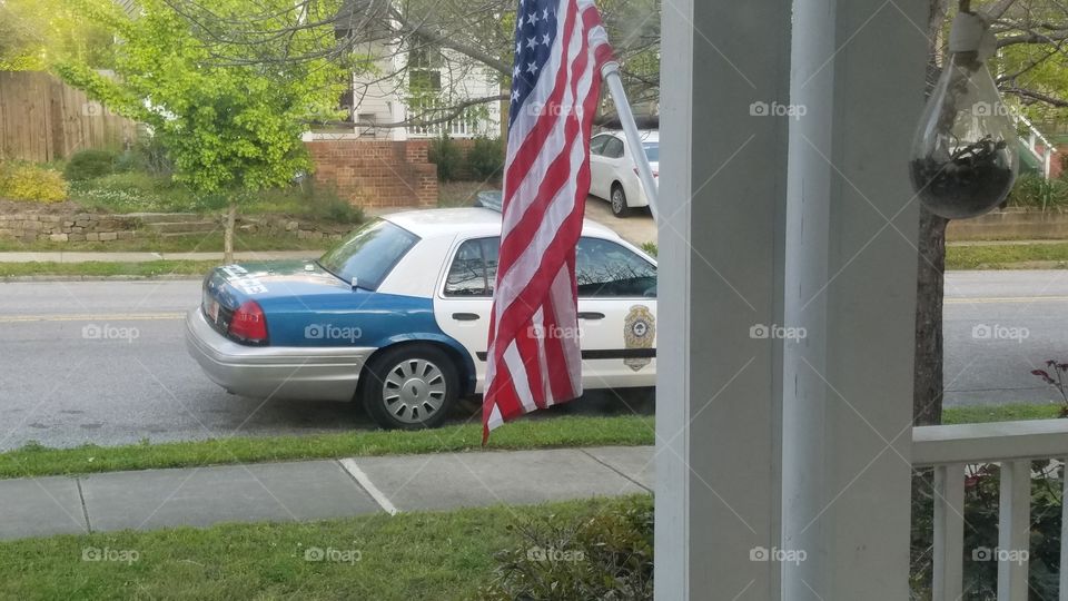 police car in front of house with American flag
