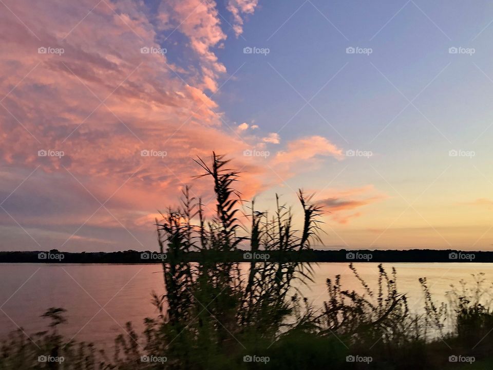 Pink clouds moving over a quiet lake 