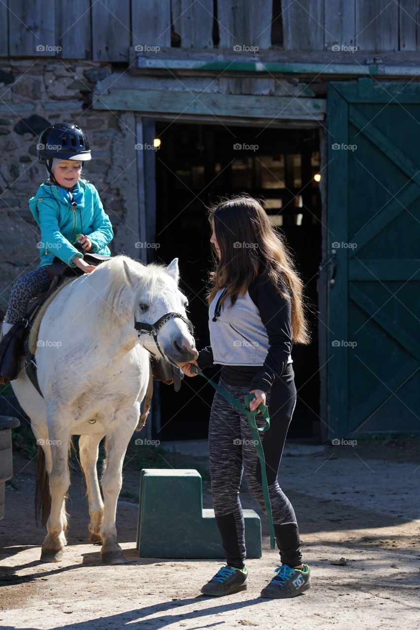 Mother looking at girl sitting on horse