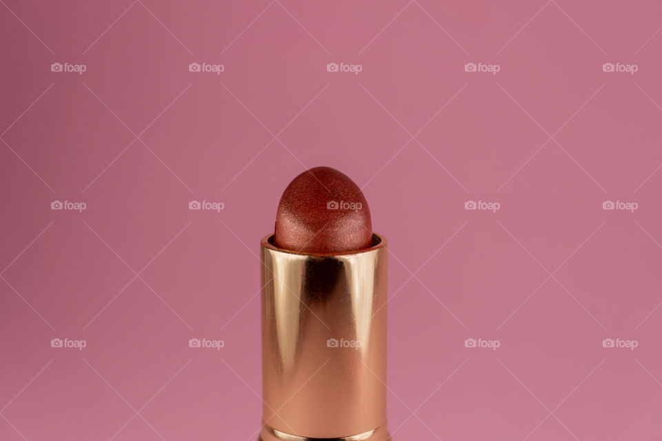 Dark red lipstick on pink background. Creative beauty concept