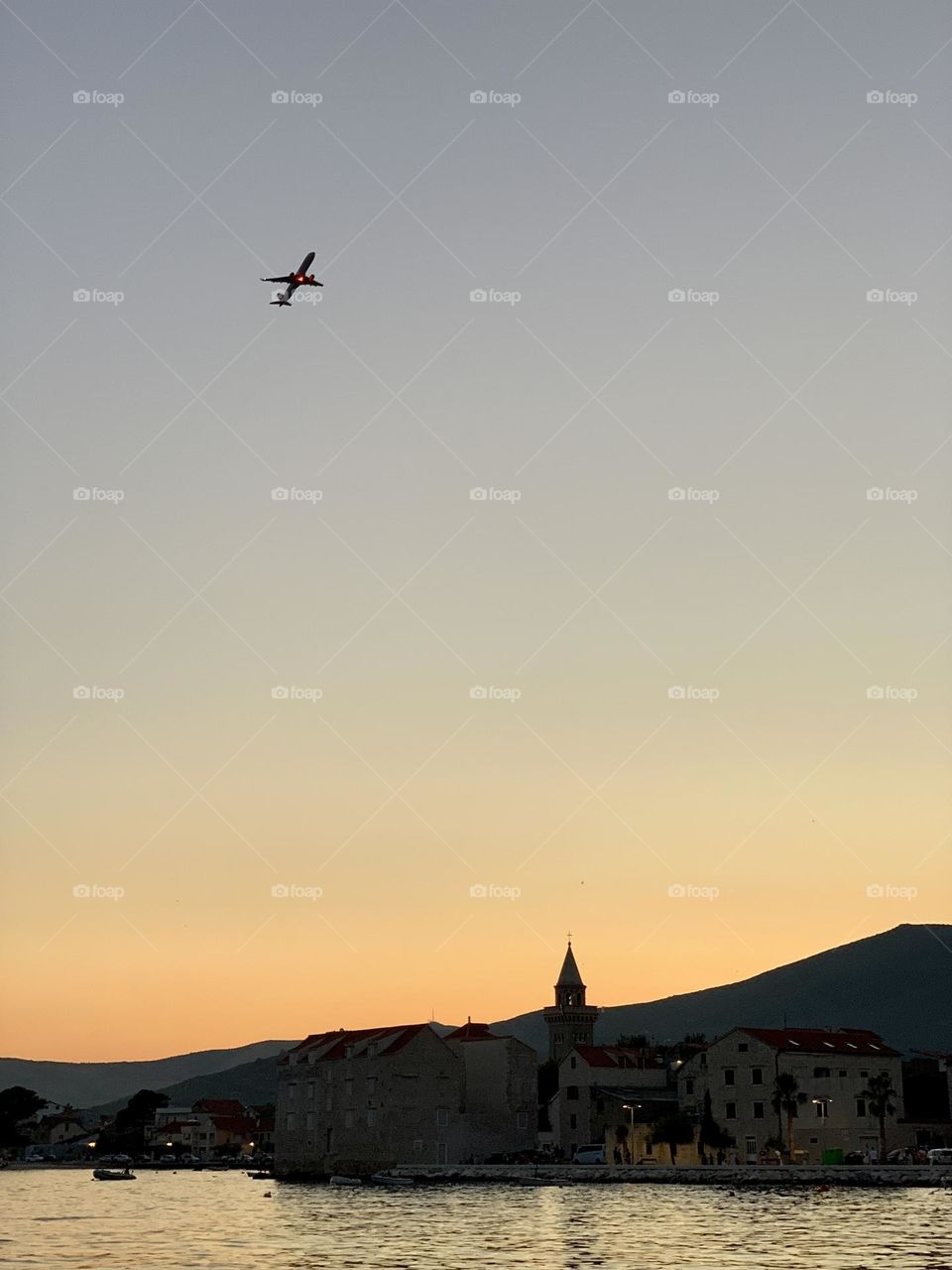 Airplane at twilight sky, sea, old town, mountains, Croatia