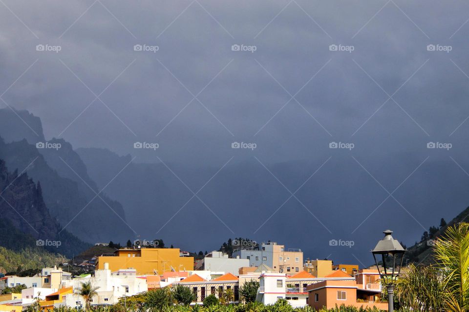 Colorful cityscape with thundery weather in the mountains in the background