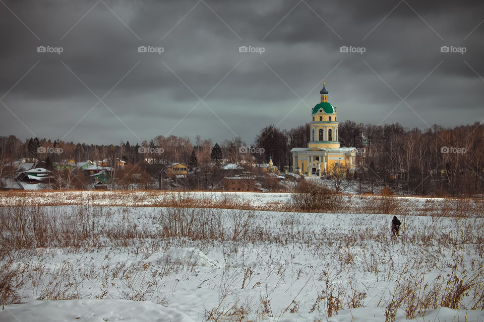 Landscapes of Russia. Fryazino Church of St. Nicholas. Early spring in Russia. Country landscape. Landscape melting snow on the field. Gray sky over the chapel church.