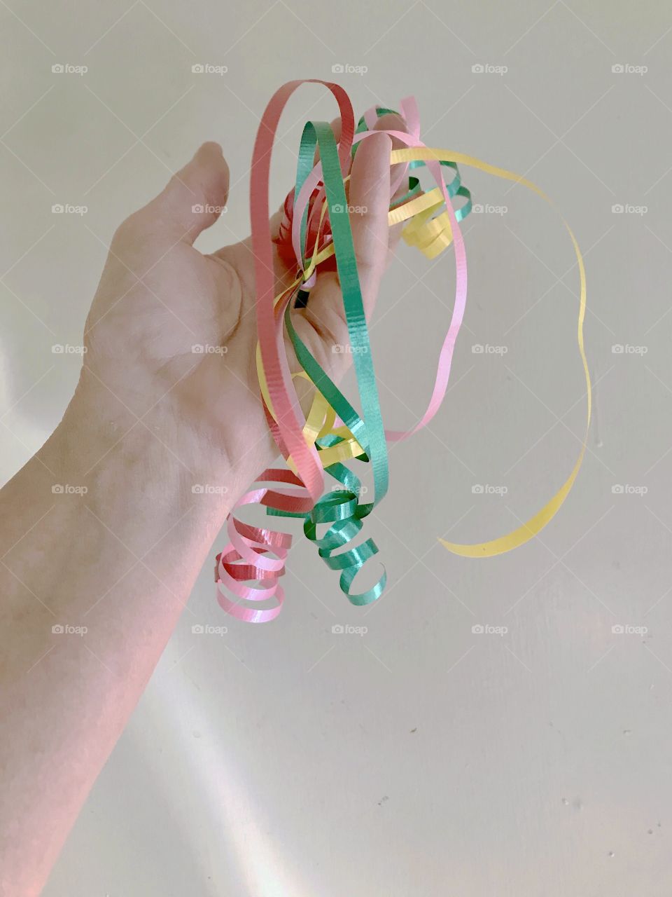 A woman’s hand holds a pop of colorful party ribbons against a white background!