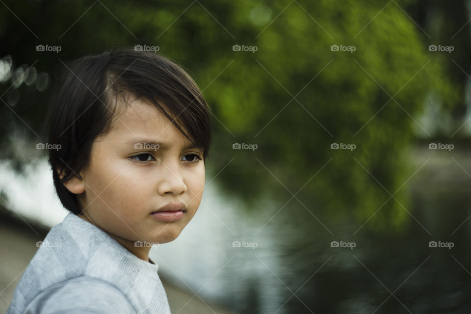 outdoor portrait of happy young eurasian boy on a blurry out of focus bokeh foliage background