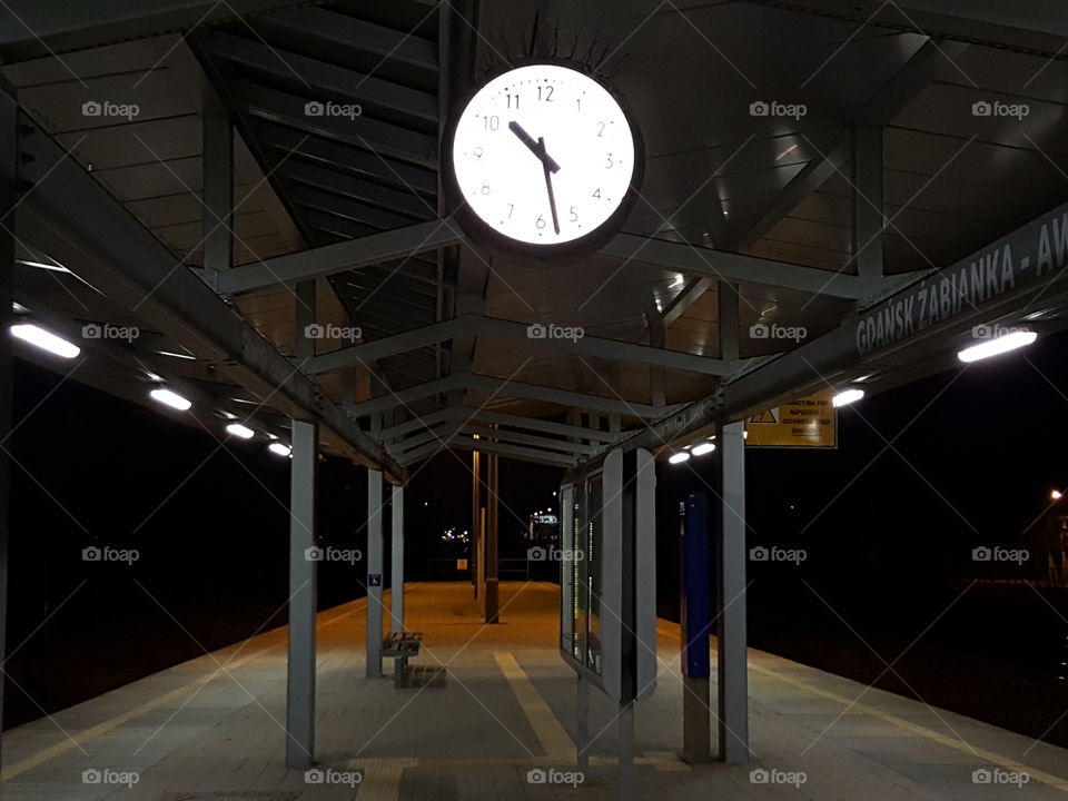 Empty train station platform in Gdansk Zaspa at late evening with a big clock showing 10:30 pm