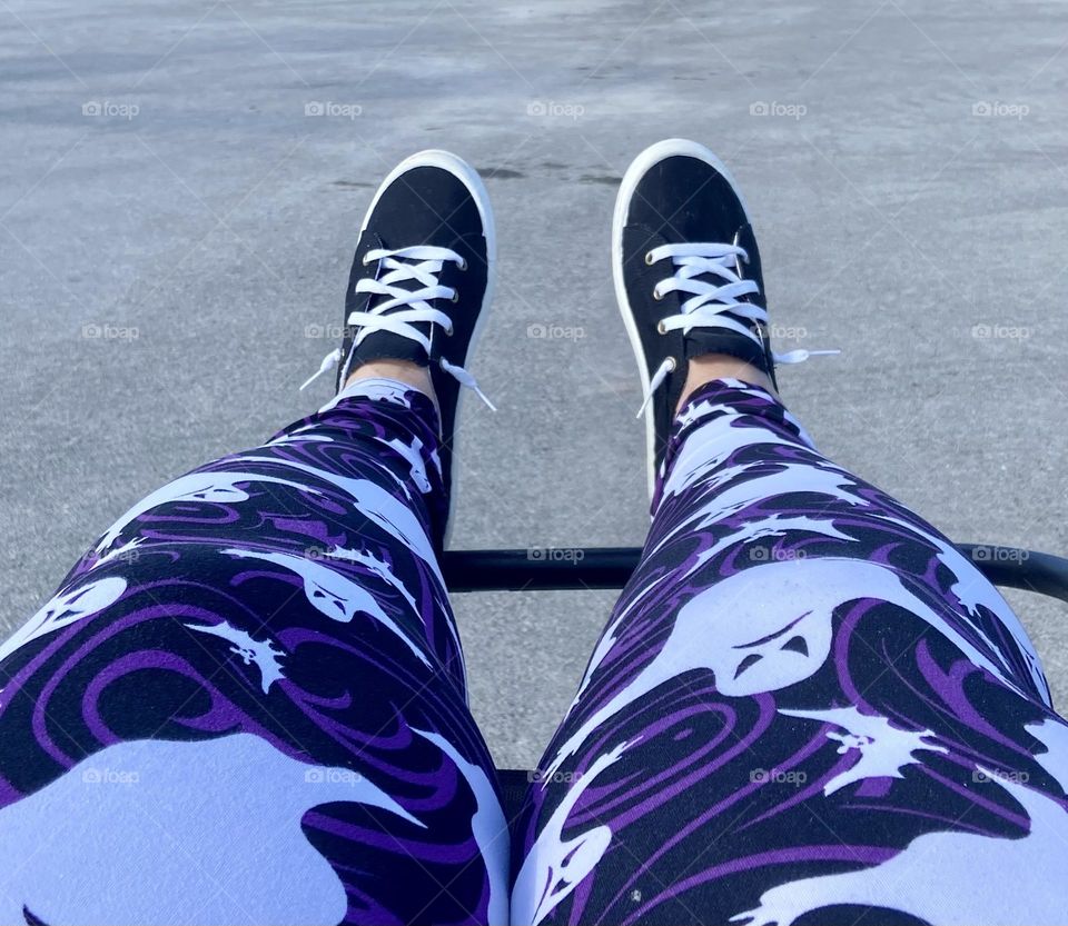 A pair of legs with black shoes and purple, white, and black ghost printed leggings