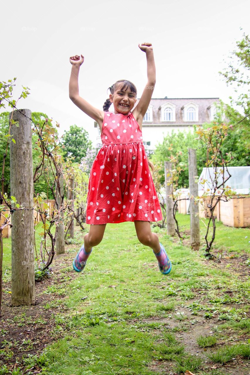 Wildly dancing cute girl in a red polka dot dress