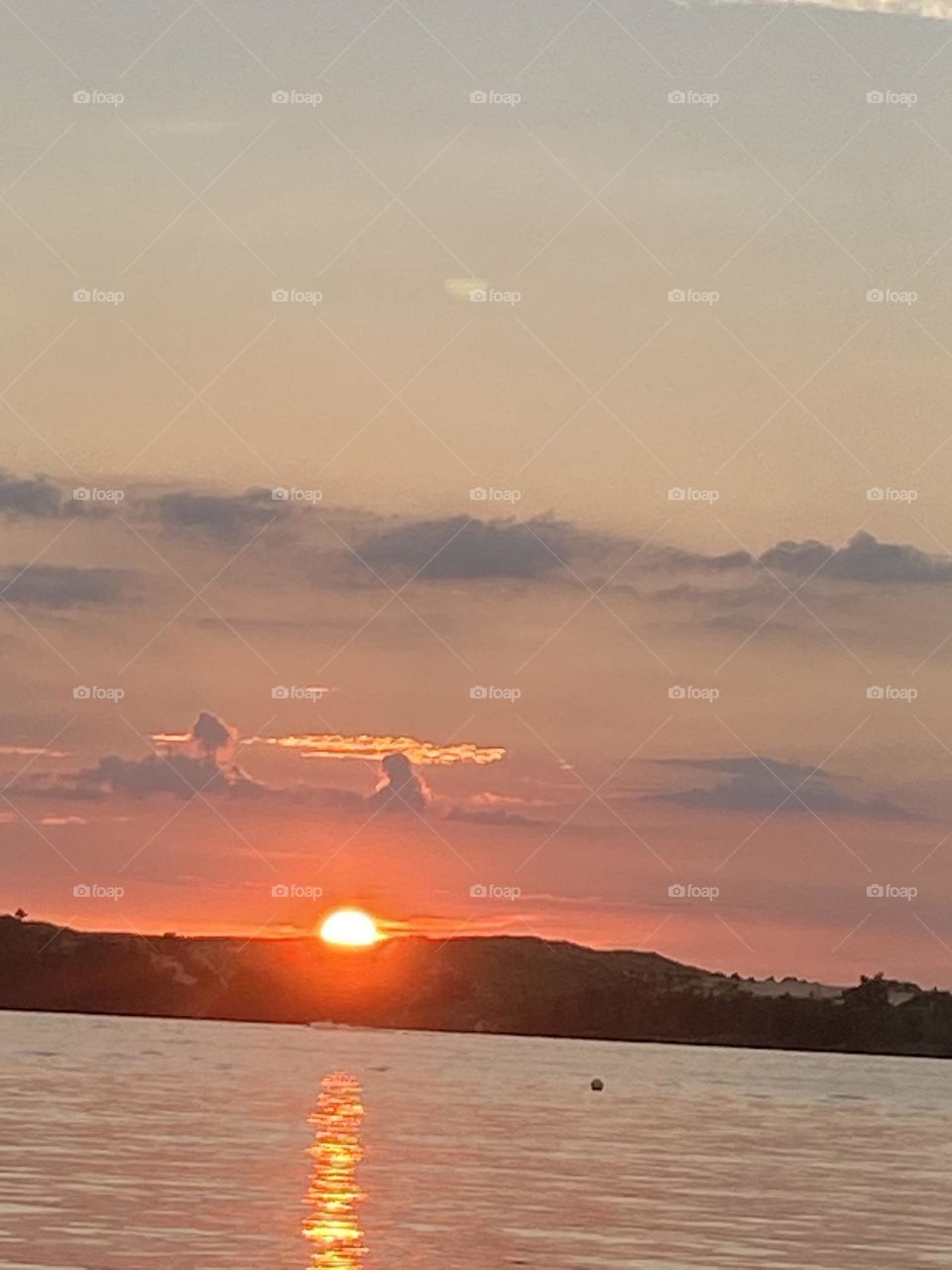 A beautiful orange sunset with a man and his best friend in the clouds above the sun in the horizon. 