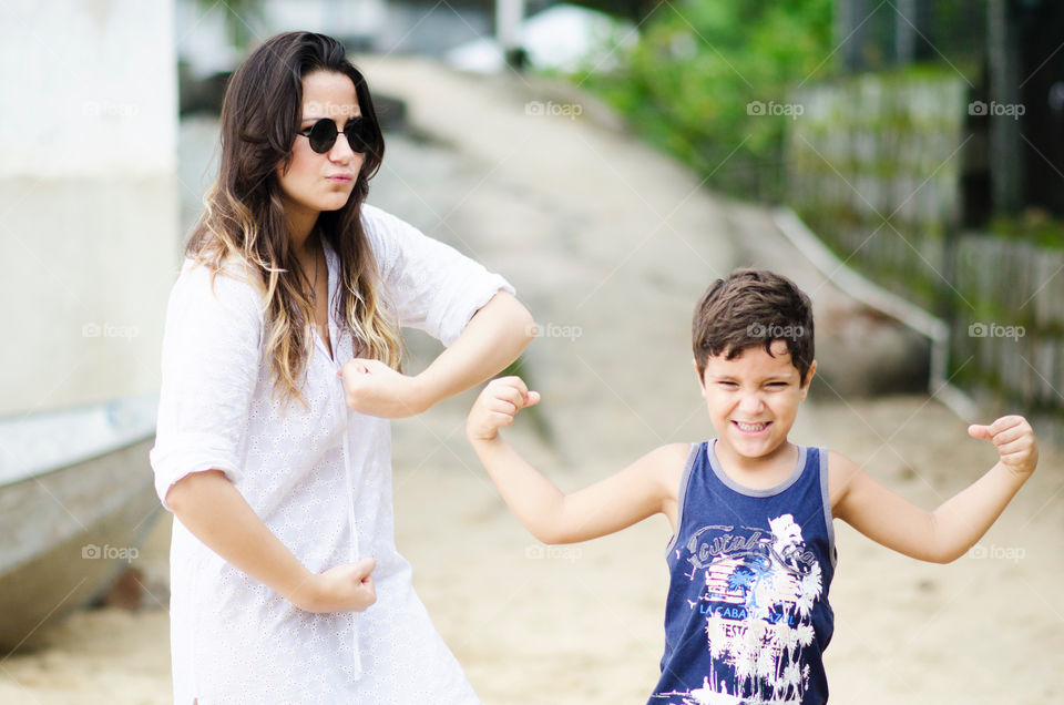 Mother and son showing strong arm at outdoors