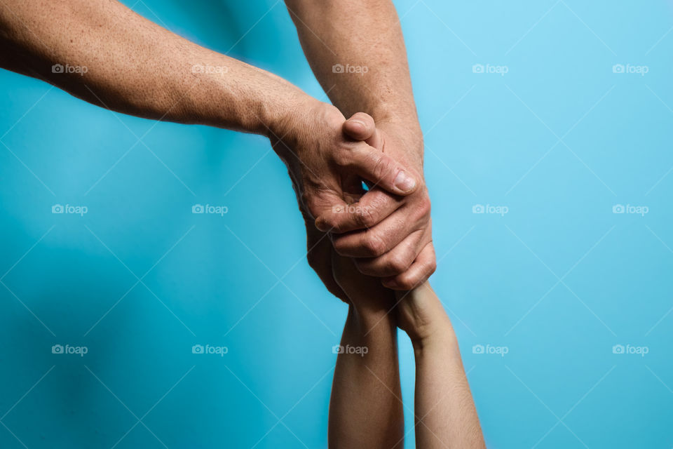 Intertwined hands of a young man and woman. On blue background.