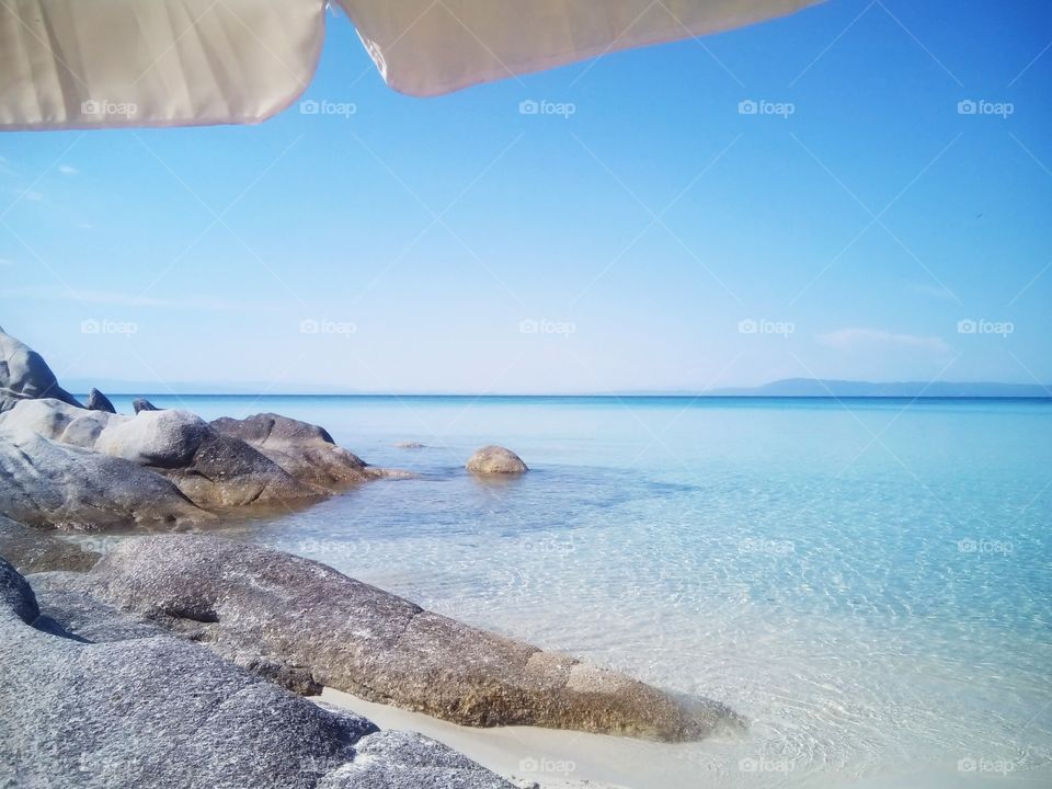 The Orange Beach, Sarti. Blue lagoon. Rocky beach. Under sun umbrella