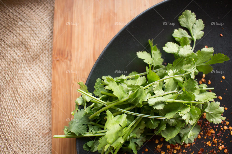 Cilantro and spices. Coriander and spices on a black plate and rustic bamboo and burlap background