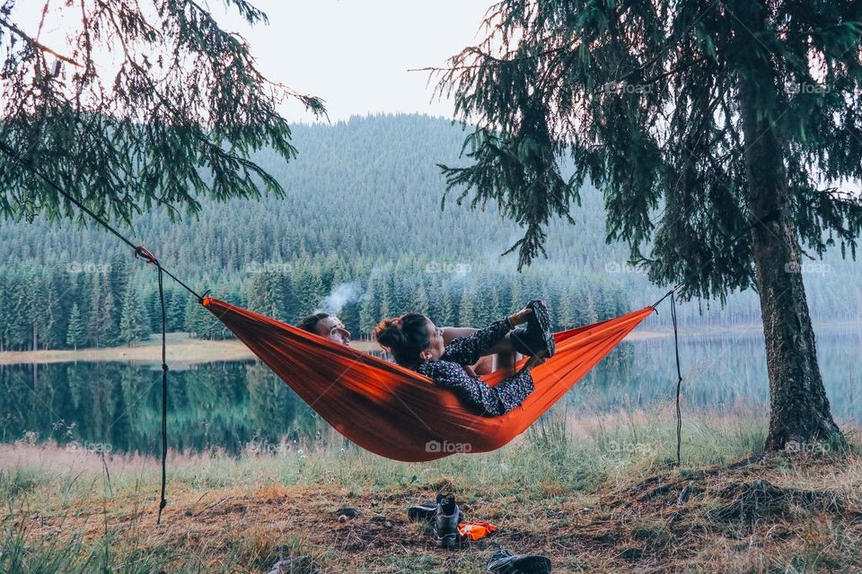 couple of lovebirds sitting in a hammock just when the night is about to show up