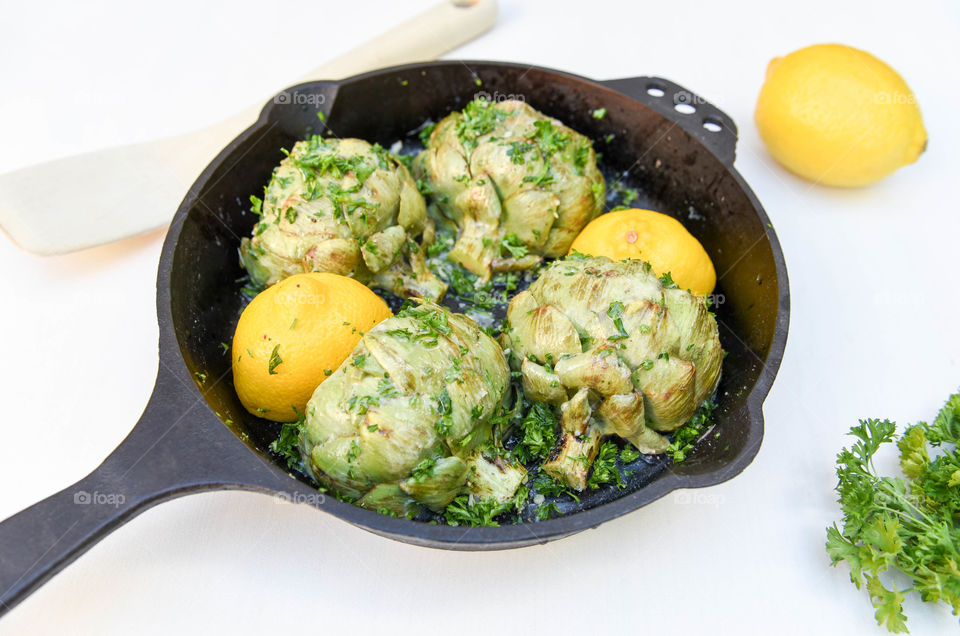 Close-up image of a lemon and artichoke dish in a cast iron skillet