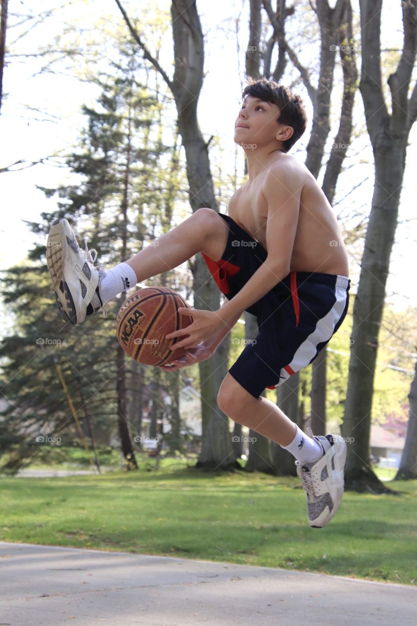 Boy jumping in air during basketball trick