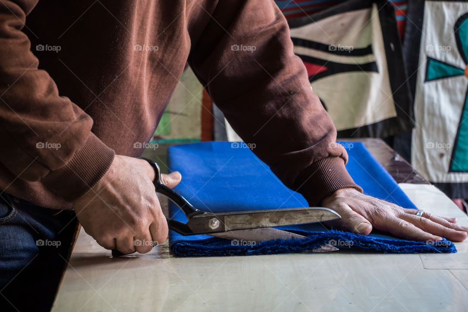 Tailor cutting this textile and taking measurements