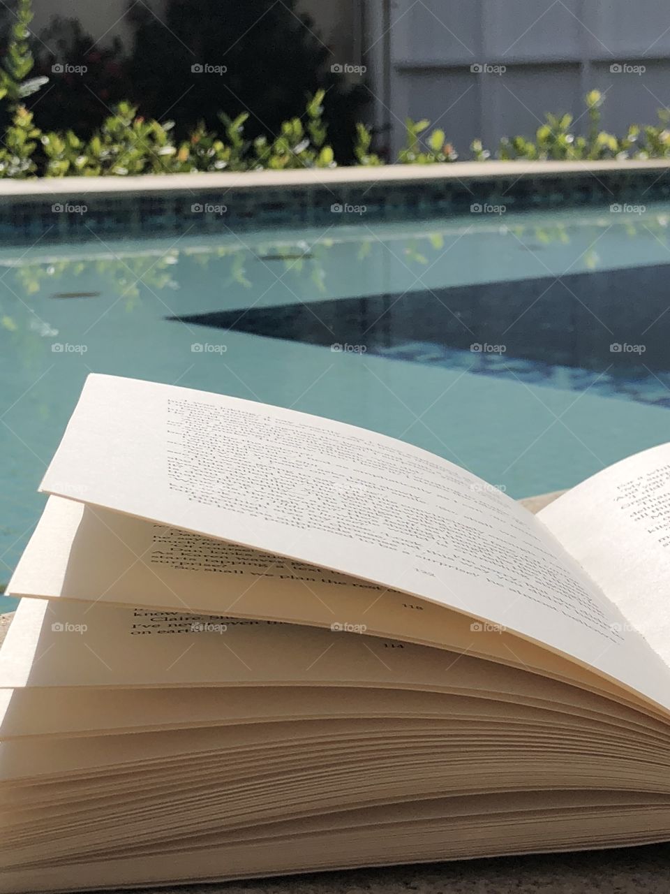 A book near a swimming pool on a sunny summer day