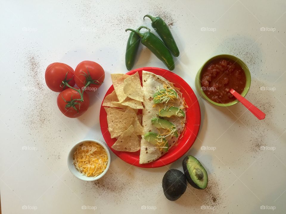 Homemade burrito on red plate with tortilla chips, accompanied by ingredients. 