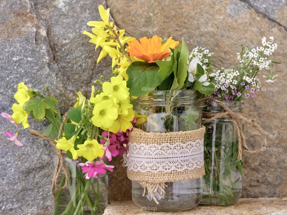 Common garden flowers and blossoms in rustic glass jars 