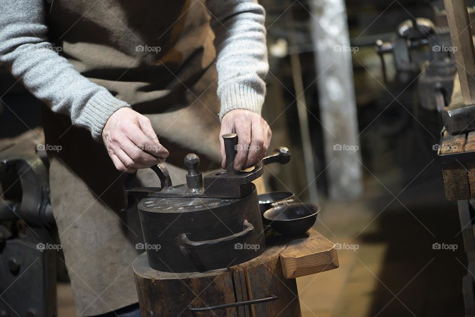 Blacksmith working at with metal at forge