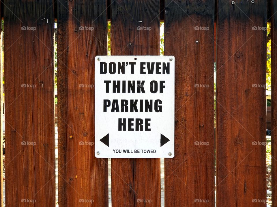 Sign on wood fence:  Don't even think of parking here