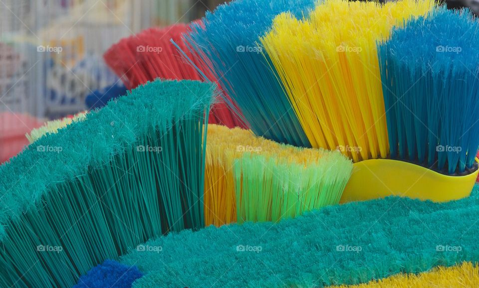 Colorful brooms lined up outside a hardware store in Brooklyn, New York City.
