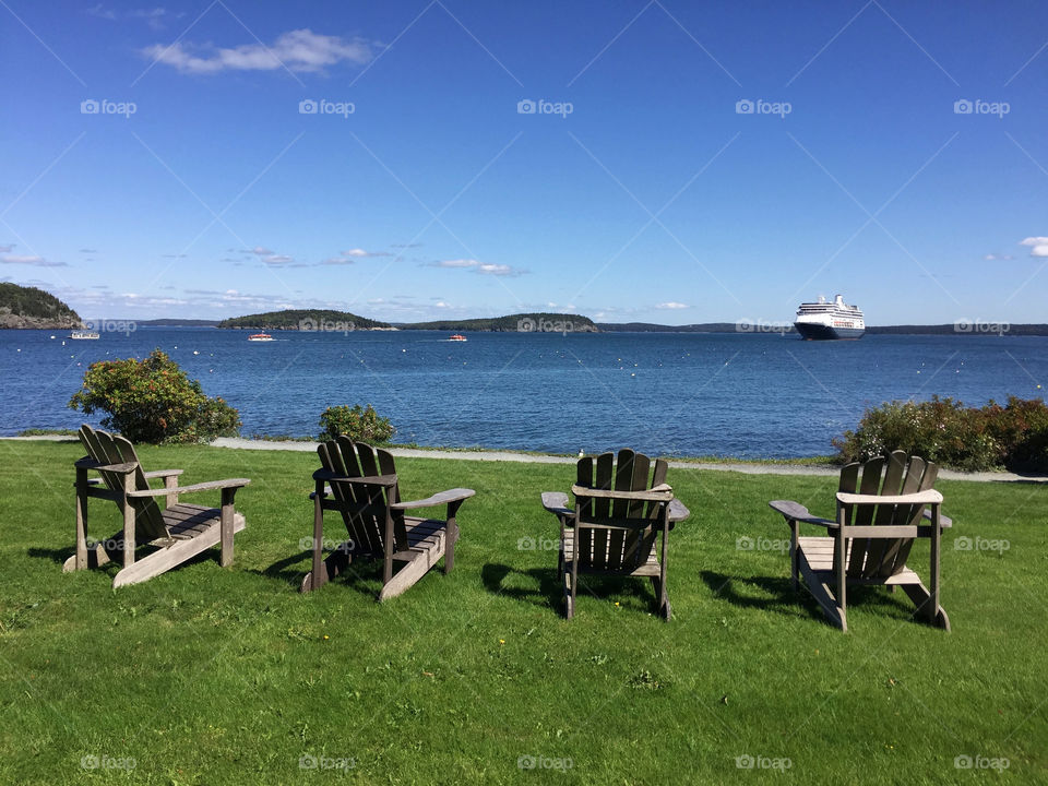 Landscape with four Adirondack chairs and a cruise ship